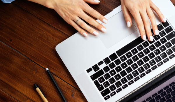 Closeup photo of female hands with a laptop. Female freelancer c