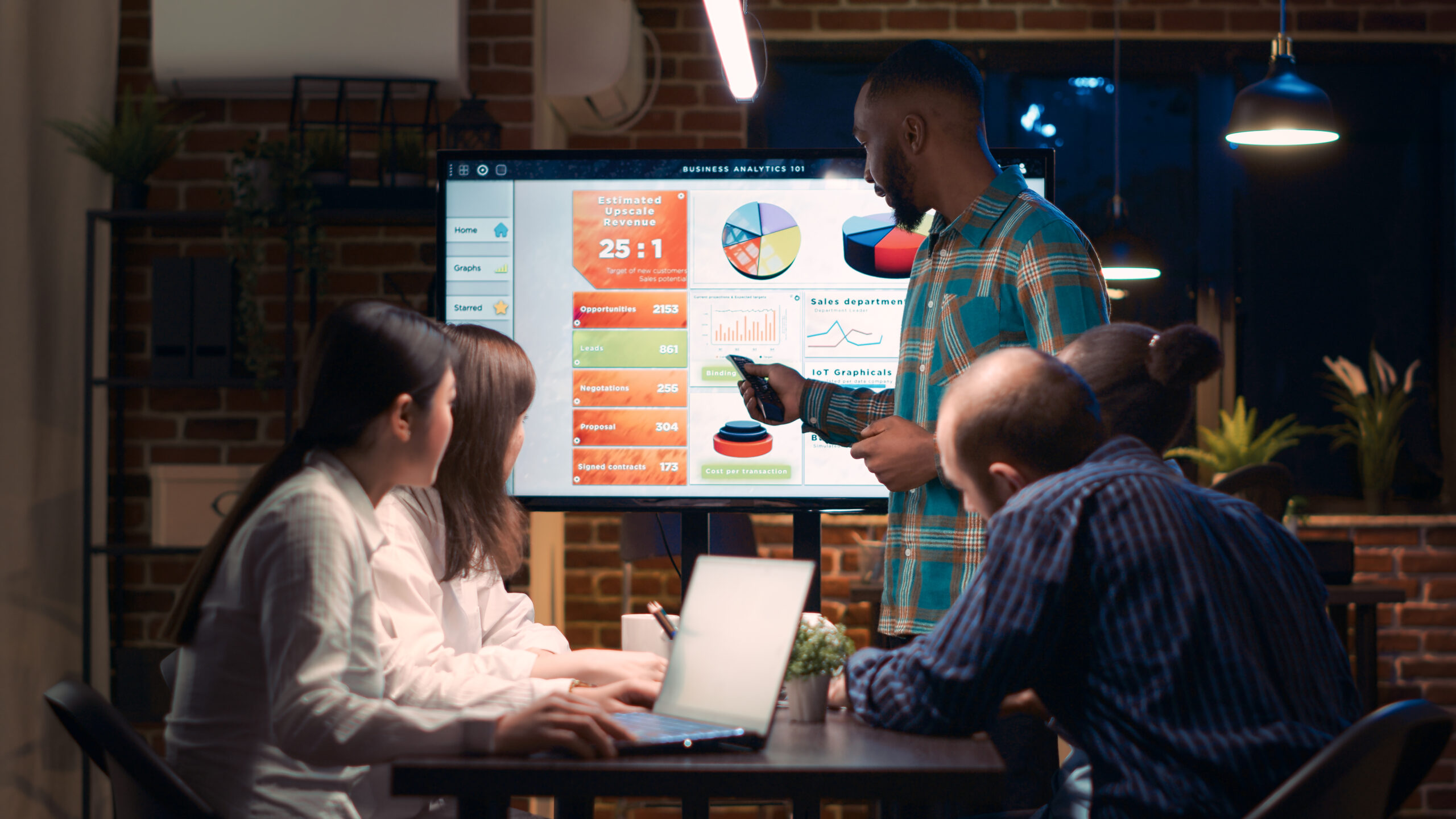 A black employee giving analytics report presentation in business meeting, showing statistics data on digital board screen. Office worker marketing research, strategy planning