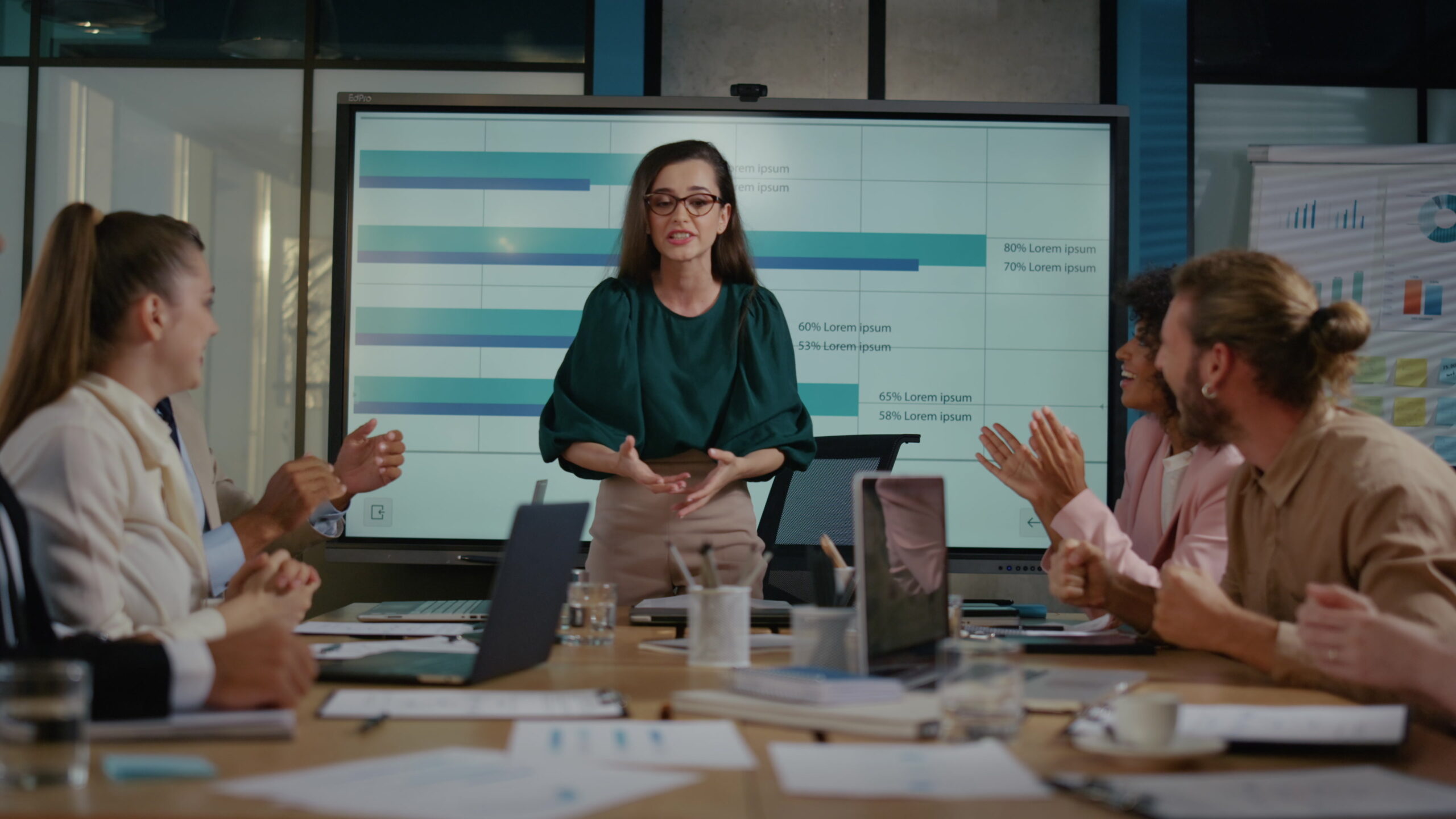 Female leader celebrating success with coworkers in conference room. Multi ethnic business team stacking hands together. Happy team members clapping hands during meeting