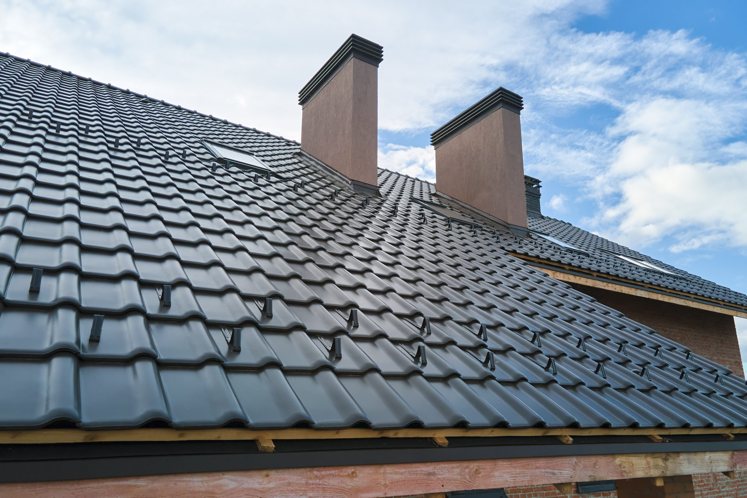 Closeup snow guard for safety in winter on house roof top covered with ceramic shingles. Tiled covering of building.