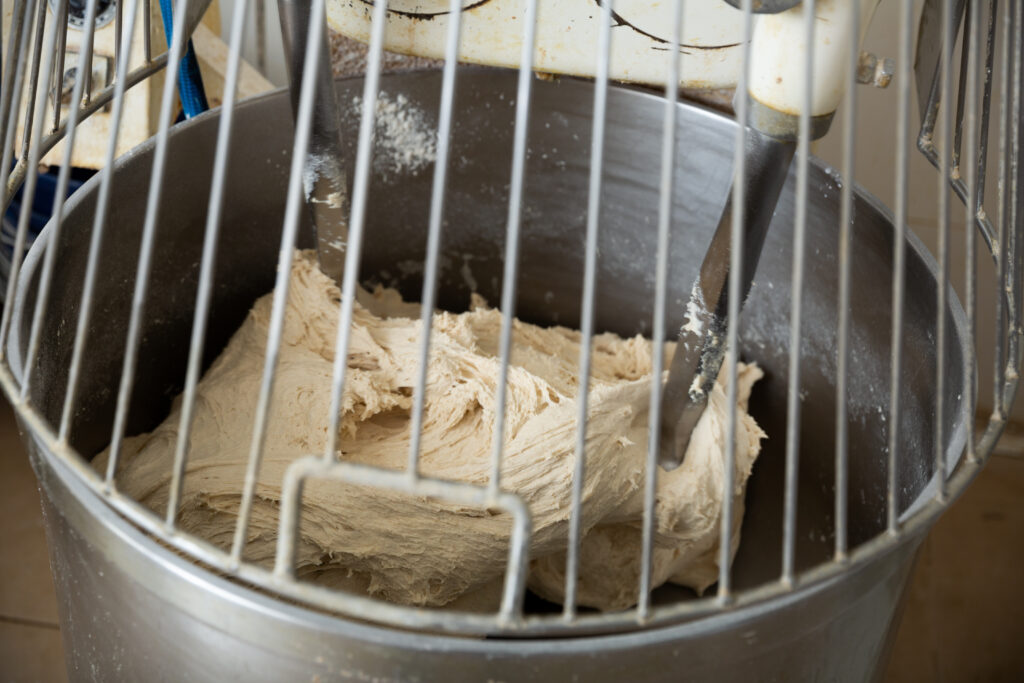 A dough-mixing machine with fresh dough inside. The machine is old and shows signs of wear and tear.